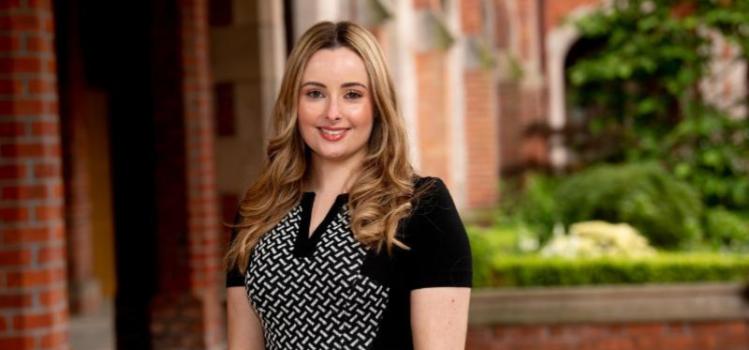 Smiling woman standing outside the Quad at Queen's University, pictured to mark Carers Week.